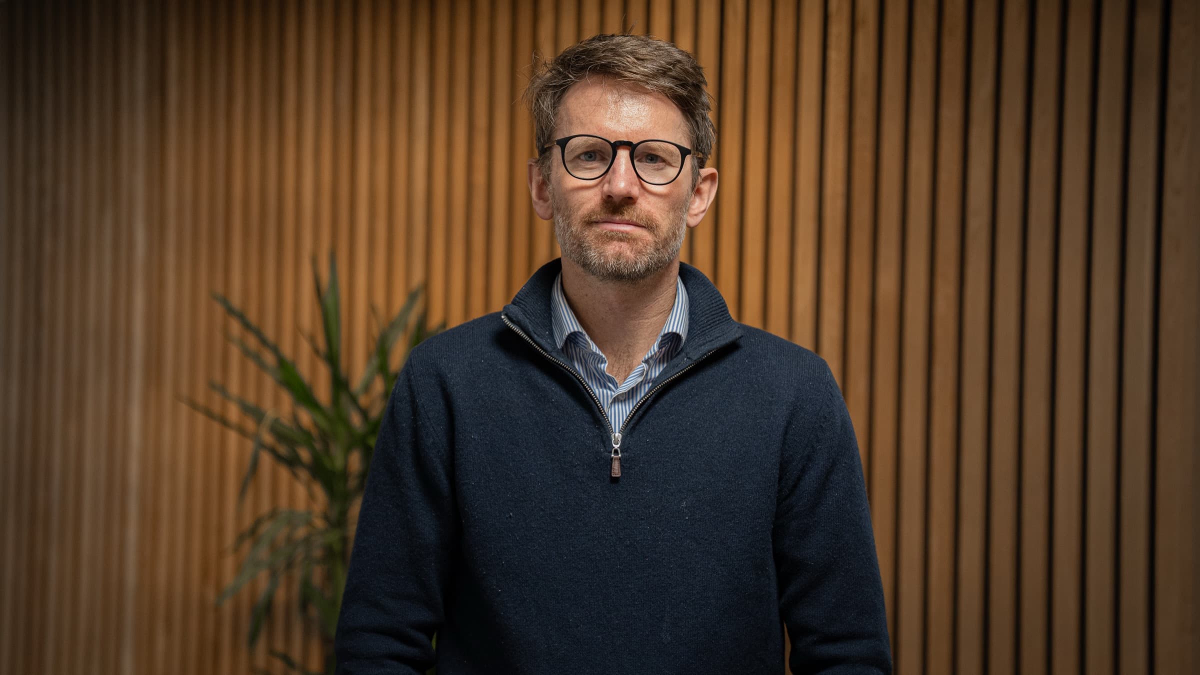 Ansatt hos Byggkon fotografert mot trepanelet i lokalene
